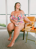 Femme assise sur une chaise portant un maillot deux-pièces imprimé tropical