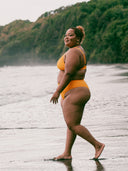 femme portant un bikini jaune debout sur une plage