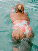 Femme ronde nageant dans une piscine avec un maillot une pièce imprimé corail